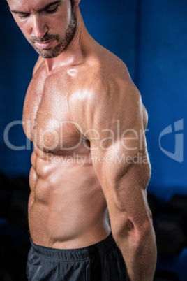 Shirtless athlete looking at biceps