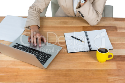 Businesswoman using laptop with diary and black coffee on table