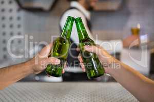 Two men toasting a bottle of beer