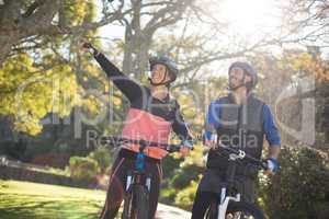 Biker couple with mountain bike pointing in distance