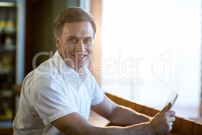 Smiling man using a digital tablet in cafÃ?Â©