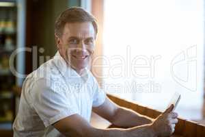 Smiling man using a digital tablet in cafÃ?Â©