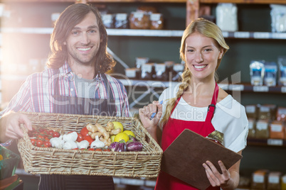 Male staff holding basket of vegetables and female staff with clipboard