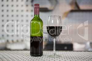 Glass of red wine and bottle on counter