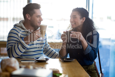 Smiling young couple having coffee in cafe