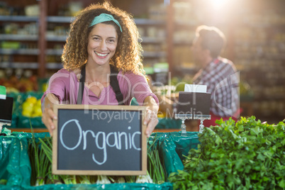 Smiling staff holding organic sign board in organic section