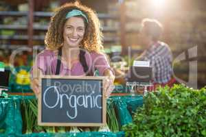 Smiling staff holding organic sign board in organic section
