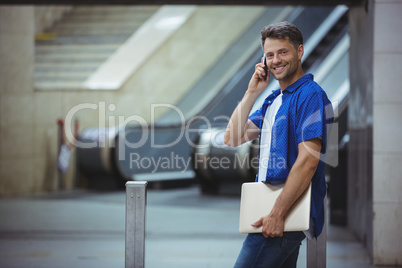 Handsome man holding laptop and talking on mobile phone