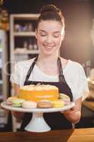 Waitress holding dessert on cake stand in cafe