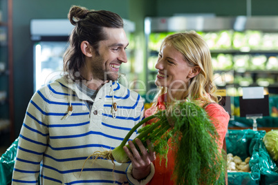 Happy couple holding fennel in organic section