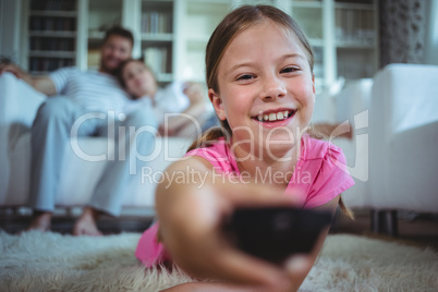 Smiling girl lying on rug and changing channels