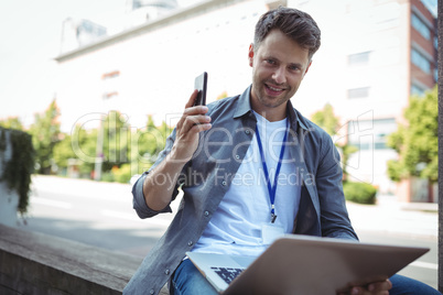 Handsome business executive holding mobile phone and laptop