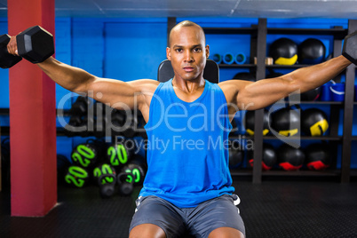 Determined male athlete exercising with dumbbells