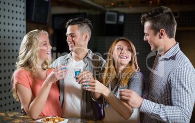 Two couple standing at bar counter and having tequila shots