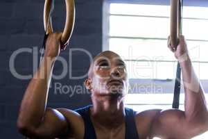 Close-up of man using gymnastic rings in gym