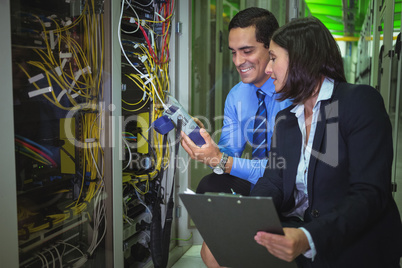 Technicians using digital cable analyzer while analyzing server