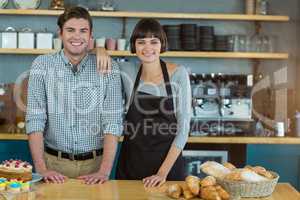 Portrait of man and waitress standing at bread counter