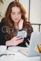 Beautiful executive using cellphone at creative office