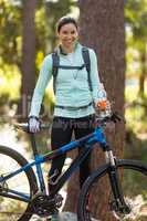 Female biker standing with mountain bike in forest