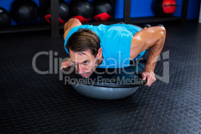 Serious man using BOSU ball in gym