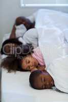 Family sleeping on bed