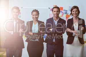 Group of businesspeople with arms crossed standing in front of whiteboard