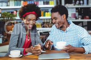 Man and woman interacting with each other while having cup of coffee