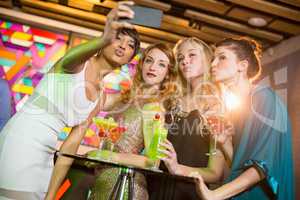 Group of friends taking selfie from mobile phone while having cocktail