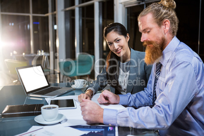 Businesswoman and colleague discussing over blueprint