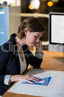 Businesswoman working on a blueprint in the office