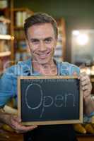 Portrait of a male staff holding a open sign