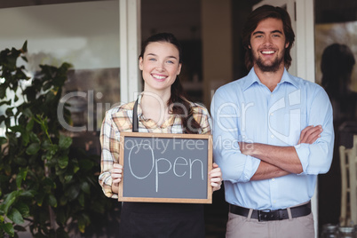 Man and waitress holding chalkboard with open sign