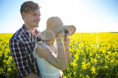 Couple taking picture from camera in mustard field