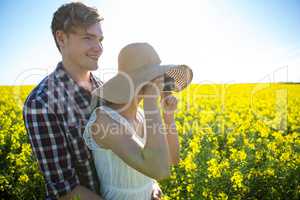 Couple taking picture from camera in mustard field