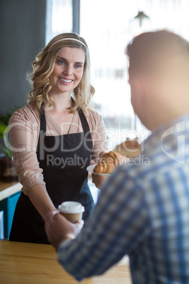 Waitress serving a cup of coffee and croissant to customer