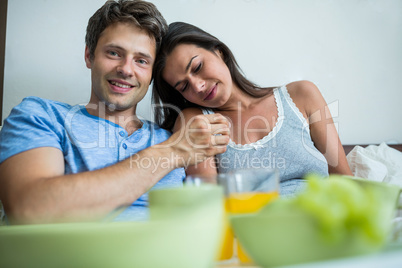 Smiling couple having breakfast on bed
