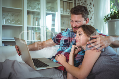 Happy couple using laptop in living room