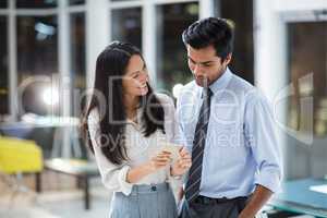 Businesswoman showing mobile phone to colleague