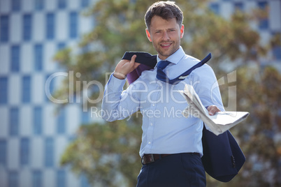 Portrait of businessman holding blazer and newspaper