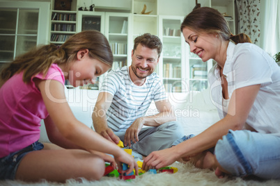 Parents and daughter playing with building blocks