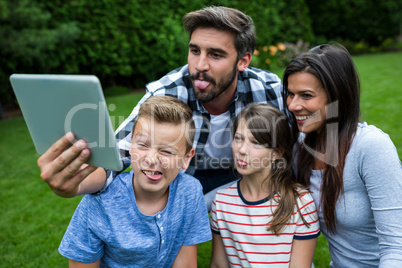 Happy family taking a selfie from digital tablet in park