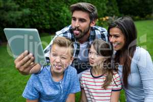 Happy family taking a selfie from digital tablet in park