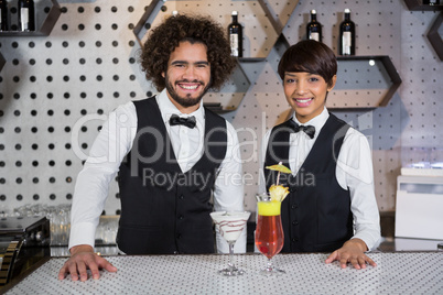 Waitress and waiter standing in bar counter with glass of cocktail
