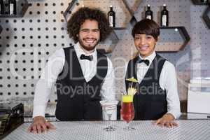 Waitress and waiter standing in bar counter with glass of cocktail