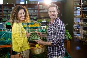 Happy couple buying vegetables in organic section