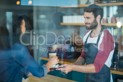 Waiter serving a cup of cold coffee to customer at counter