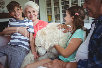 Grandparents and grandchildren sitting on sofa with pet dog