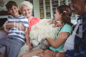 Grandparents and grandchildren sitting on sofa with pet dog