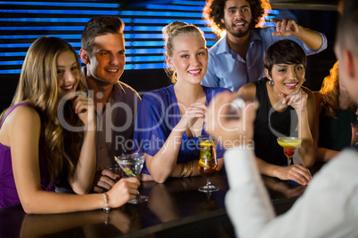 Happy friends standing at bar counter