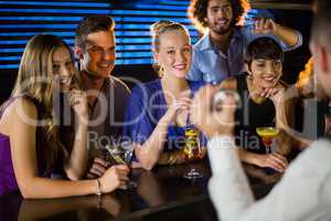 Happy friends standing at bar counter